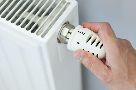 A person opening a thermostatic radiator valve to protect their heating system