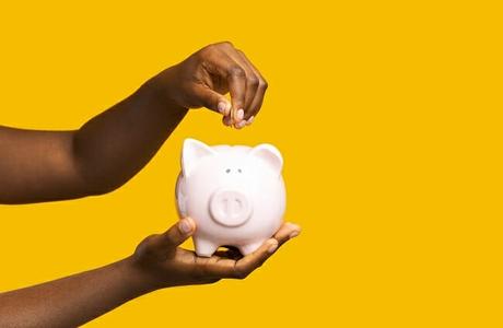 A black woman putting money in a piggy bank