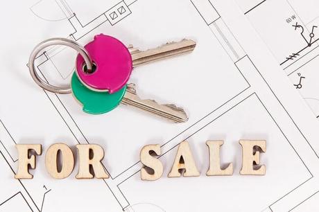 A set of house keys with a for sale sign