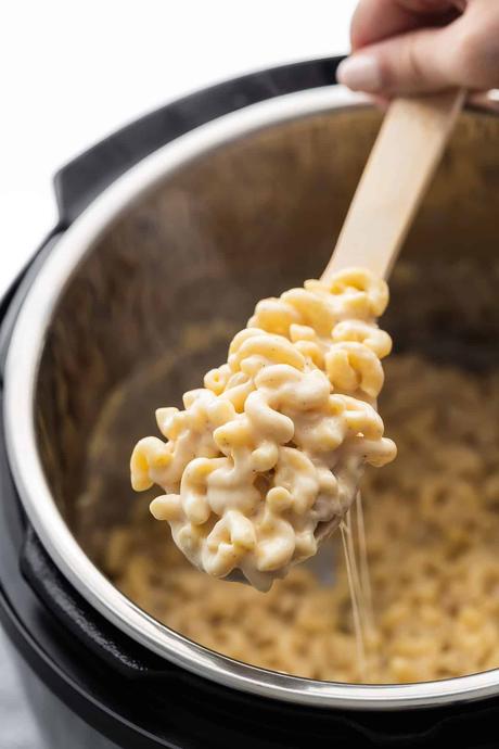 close up shot of macaroni and cheese on spoon, lifted above instant pot