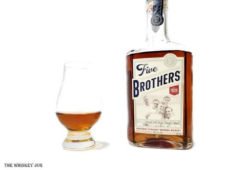 White background tasting shot with the Five Brothers Bourbon bottle and a glass of whiskey next to it.