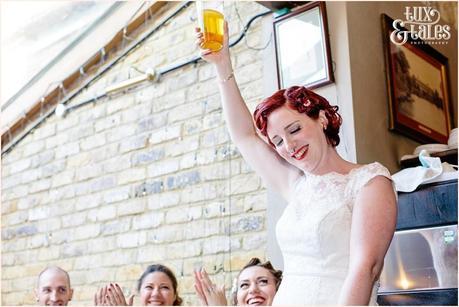 Bride holds up a pint in her speech at tattoo wedding red and black details 