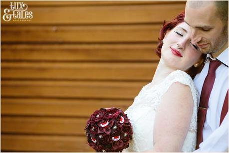 Bride and groom embrace in front of orange wall at London wedding