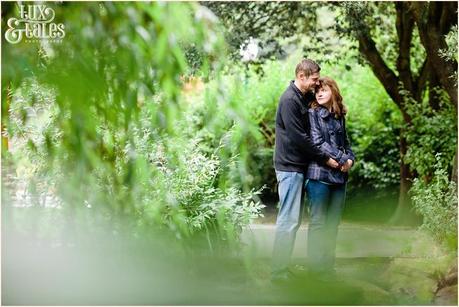 Engaged couple cuddle behind trees in Scarborough 