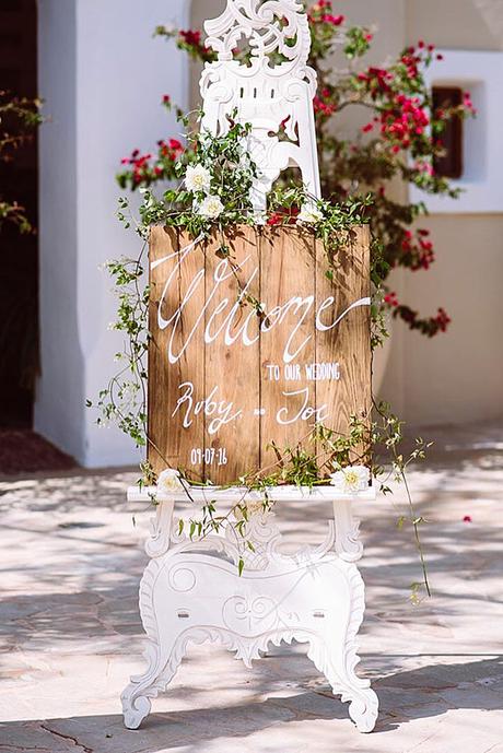 popular wedding signs on a white tracery stand a wooden board with inscriptions is decorated with green and flowers