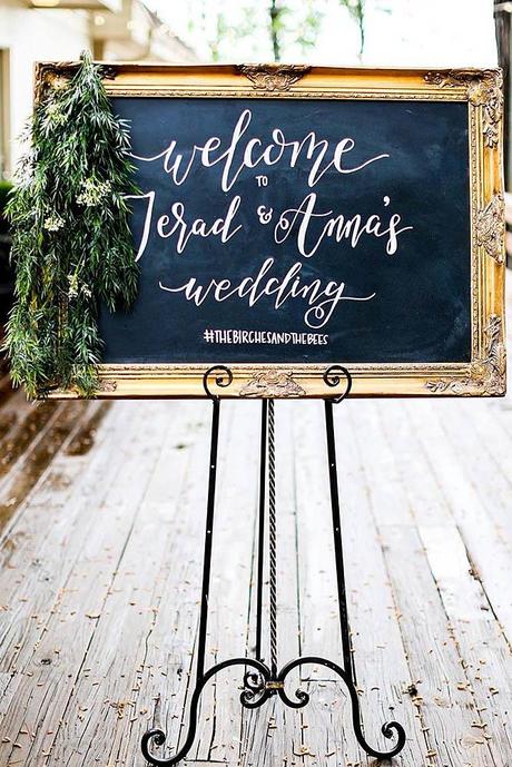 popular wedding signs on a black background in a golden elegant frame adorned with greenery wedding venue via instagram