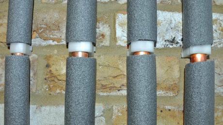 Four copper water pipes in gray foam insulation 