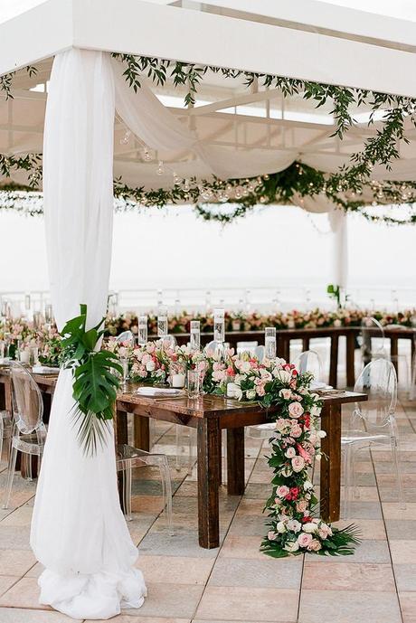 summer wedding trends reception under white tent with flower table runner and hanging greenery the ganeys