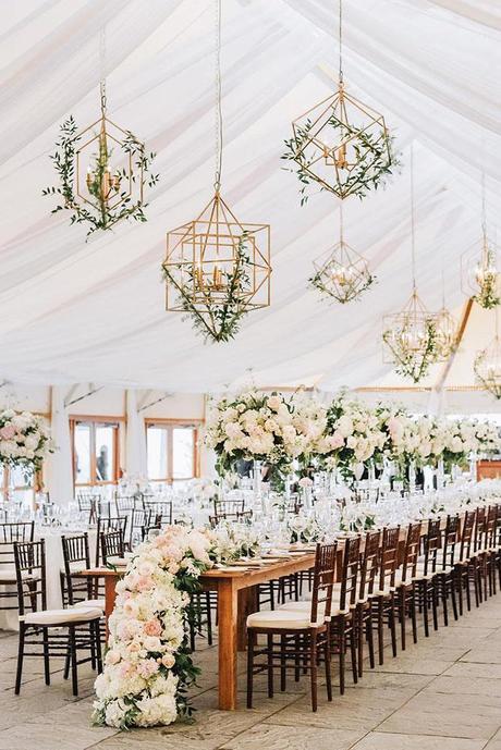 summer wedding trends reception under the tent with tall centerpieces white flower table runner and hanging geometry candles with greenry lenamirisola