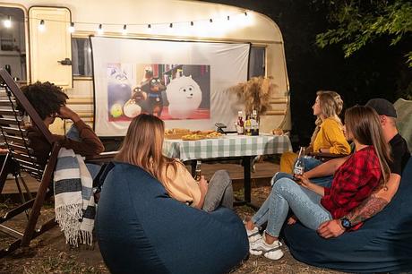 Friends watching a movie with Prima Projector during camping