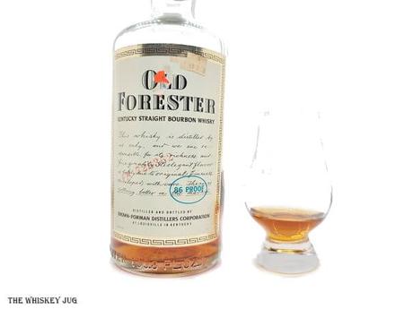 White background tasting shot with the 1981 Old Forester Kentucky Straight Bourbon bottle and a glass of whiskey next to it.