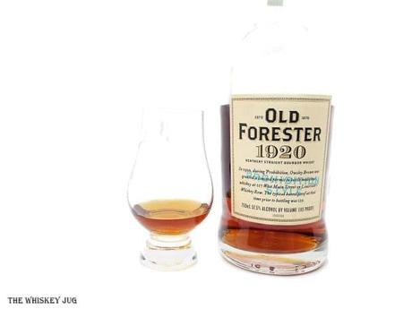 White background tasting shot with the Old Forester 1920 Prohibition Style bottle and a glass of whiskey next to it.