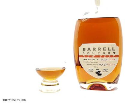 White background tasting shot with the Barrell Bourbon New Year 2022 bottle and a glass of whiskey next to it.