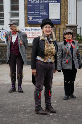 Photograph of three dancers standing in the street in molly dancing dress.