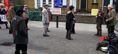 Photograph of dancers and two musicians stood in the street