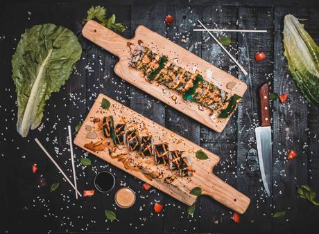 two trays of sushi and a knife next to them