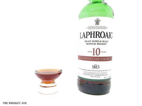 White background tasting shot with the Laphroaig 10 Year Sherry Oak Finish bottle and a glass of whiskey next to it.
