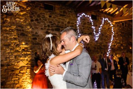 Bride and groom during first dance with heart shaped fiary lights int he background 