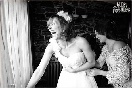 Bride laughs as they close up her wedding dress at New House Farm in the Lake District