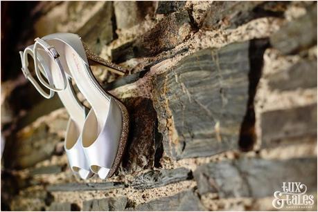 Shoes hang from a stone wall at Lake district wedding New House Farm 