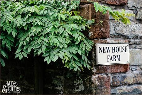 Sign saying New House Farm next to some ivy on a stone wall 