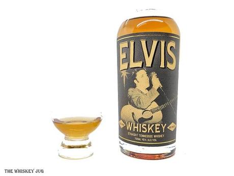 White background tasting shot with the Elvis Tennessee Whiskey bottle and a glass of whiskey next to it.