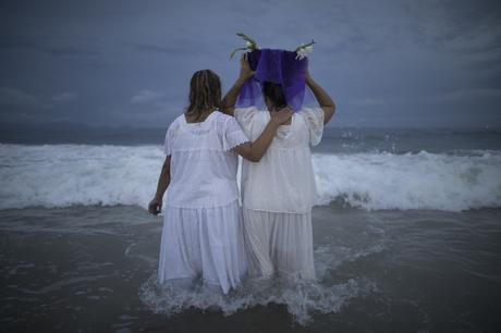 A faithful carries flowers as an offering for Yemanja, goddess of the sea, during a ceremony that is part of traditional New Year's celebrations on Co...