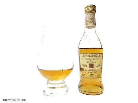 White background tasting shot with the Glenmorangie Nectar D'Or 12 Years bottle and a glass of whiskey next to it.
