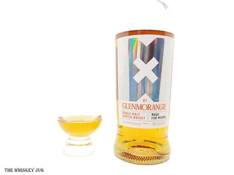 White background tasting shot with the X by Glenmorangie bottle and a glass of whiskey next to it.