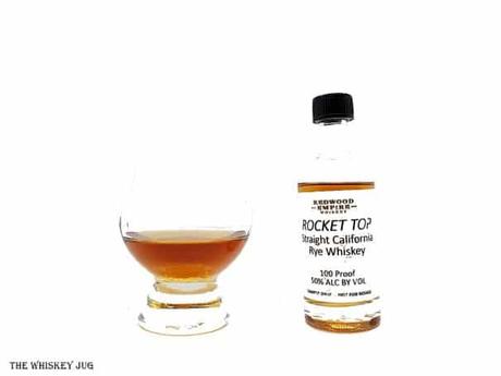 White background tasting shot with the Redwood Empire Rocket Top California Rye Whiskey sample bottle and a glass of whiskey next to it.