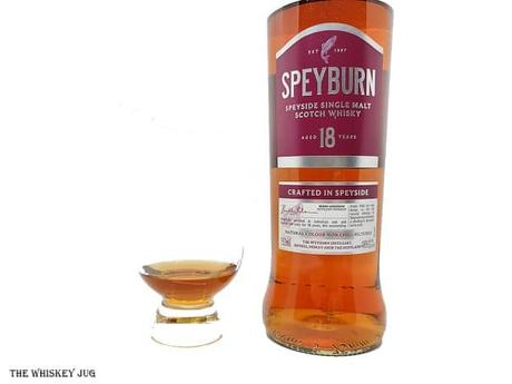 White background tasting shot with the Speyburn 18 Years bottle and a glass of whiskey next to it.