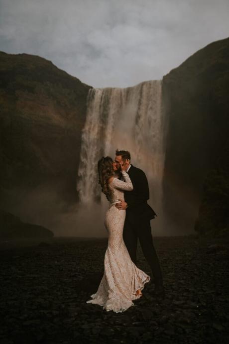 Married couple posing in front of a waterfall in Iceland