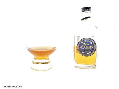 White background tasting shot with the James Ownby Reserve Tennessee Bourbon sample bottle and a glass of whiskey next to it.