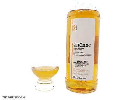 White background tasting shot with the anCnoc 12 Single Malt bottle and a glass of whiskey next to it.