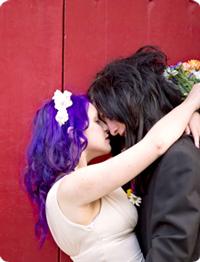 Punk Bride and Groom kiss outside a red door