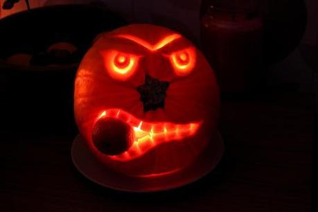 angry halloween pumpkin carved eating an orange