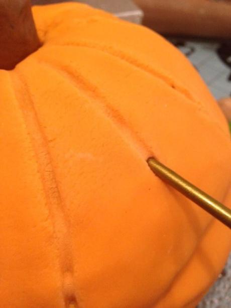 carving details into halloween pumpkin cake marking lines and ridges with paintbrush