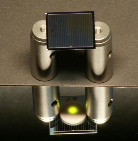 A two-sided silicon solar cell — positioned here on aluminum cylinders — is illuminated from above by an infrared laser.