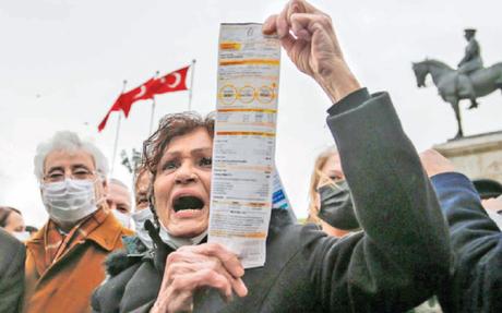 A woman displays her electricity bill during a protest against high energy prices in Ankara