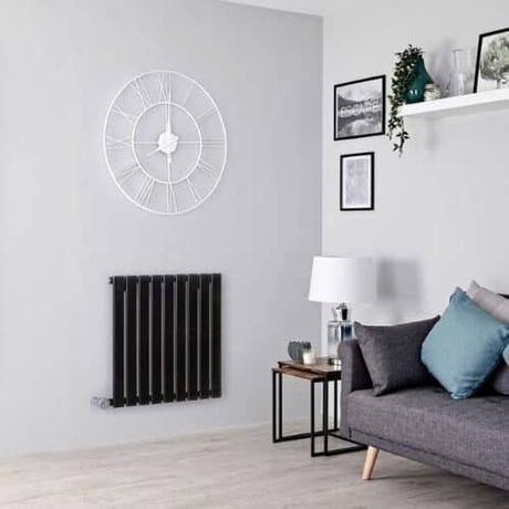 milano alpha black electric wall mounted heater in a gray living room