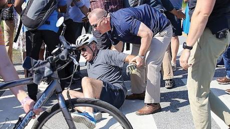 US President Joe Biden is helped by U.S. Secret Service agents after he fell trying to get off his bike to greet a crowd on a trail in Delaware on Saturday.