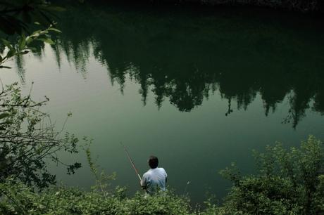 A man fishing on the riverside which is considered to be the best places to catch a big bass fish
