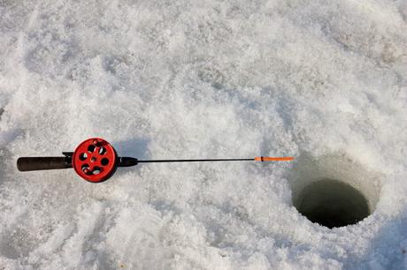 Ice fishing rod on a ground covered with ice near the fishing hole