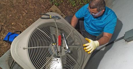 AC technician inspecting the AC’s outdoor unit