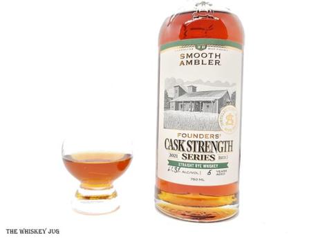 White background tasting shot with the Smooth Ambler Cask Strength Rye (Founder's Series) bottle and a glass of whiskey next to it.
