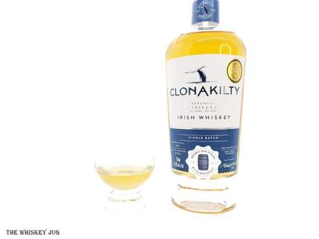 White background tasting shot with the Clonakilty Double Oak Irish Whiskey bottle and a glass of whiskey next to it.