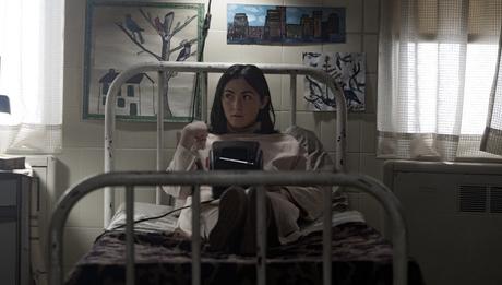 A still from Orphan: First Kill that shows Isabelle Furhmann as Leena Klammer sitting on a bed