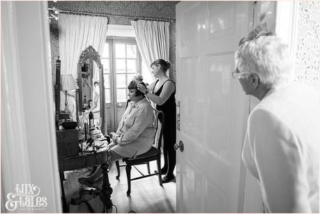 Brides mother looks on has bride has hairpiece put on at vintage wedding in yorkshire