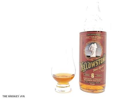 White background tasting shot with the Yellowstone Family Recipe Bourbon 6 Years bottle and a glass of whiskey next to it.