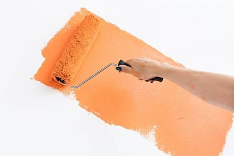 a warming orange color being painted onto a wall with a paint roller